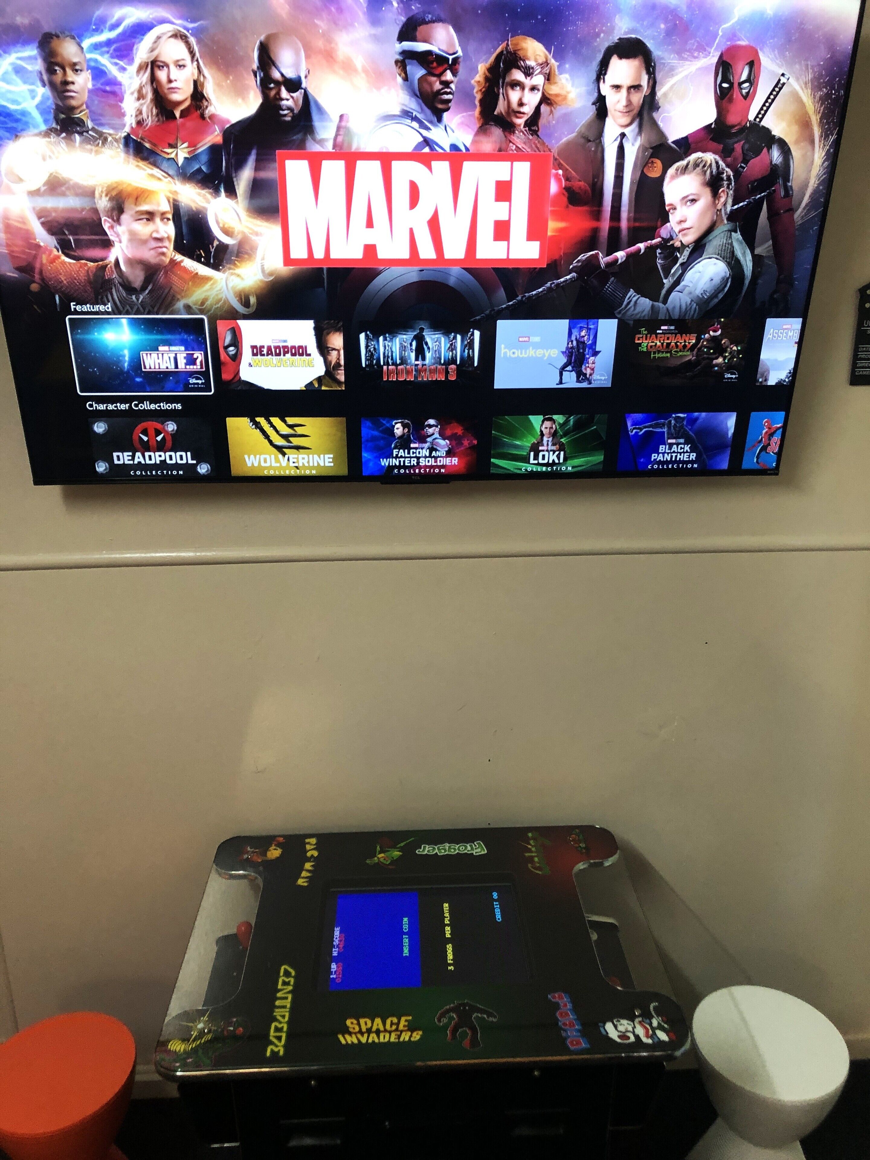 A television displaying a Marvel movie lineup, including 'What If...?' and 'Deadpool 3'.