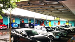 Un garaje para estacionar con varios coches bajo una estructura cubierta.