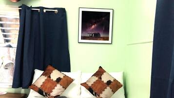 A room with a bed, a guitar, a framed picture, and a window with curtains.