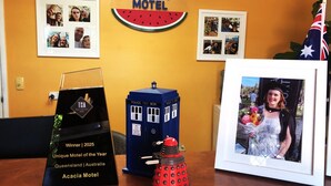 Una foto enmarcada, una cabina policial azul, un letrero del Motel Acacia y una placa que reconoce al Motel Único del Año.