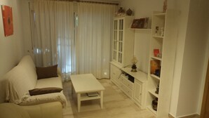 Un salon avec un canapé blanc, une petite table blanche et un meuble avec des étagères.