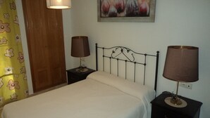 Une chambre à coucher avec un lit, deux lampes de chevet, une porte en bois et un rideau à motifs floraux.