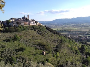 Un village perché sur une colline, avec une église et un clocher imposants, entouré d’une végétation luxuriante et surplombant une vallée.