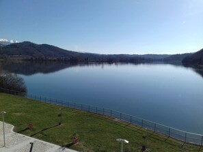 Un lac paisible, bordé d’une zone herbeuse et d’une rambarde en métal.