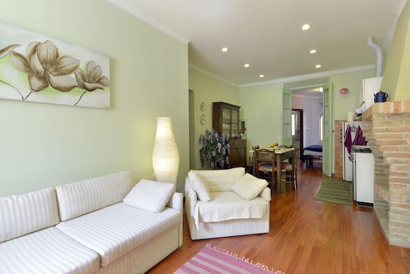 A living room with a sofa, a chair, a lamp, and a dining area with a table and chairs.