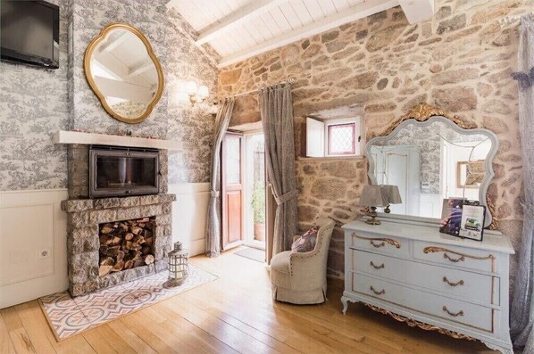 Cozy room with a stone wall, fireplace, and comfortable seating area.