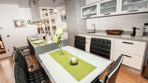 A modern kitchen with white cabinets, a built-in oven, and a sink. There is a dining table with chairs and a vase with flowers. - BEST AREA, CITY CENTER, PLAZA DEL CHARCO, IDEAL FOR FAMILIES (Puerto de la Cruz)