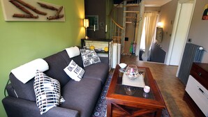 Un salon comprenant un canapé, une table basse et un escalier menant à l’étage supérieur.