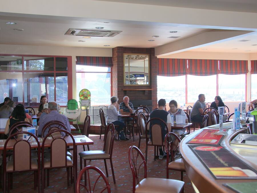 A restaurant with multiple tables and chairs, large windows, and a counter area.