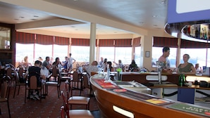 A restaurant with high tables and chairs, large windows, and a bar area.