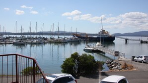 A marina with boats docked, a large ship, and a bridge.