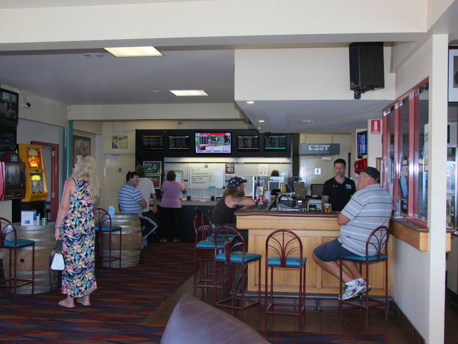 A bar area with stools, a counter, and a television screen displaying sports.