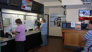 Un comptoir avec un tableau affichant le menu, un écran de télévision et un panneau indiquant que les paiements par carte de crédit ne sont pas acceptés.
