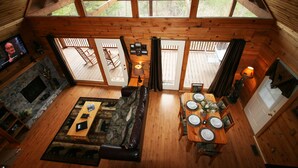 L’intérieur chaleureux d’un chalet avec une cheminée, un coin repas aménagé pour quatre personnes et un salon doté d’un canapé et d’un téléviseur.