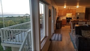 Een ruim balkon met uitzicht op zee, een keuken met houten kasten en een gezellige zithoek met een kamerkleed.