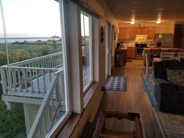 A spacious balcony with a view of the sea, a kitchen with wooden cabinets, and a cozy seating area with a patterned rug.