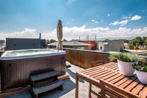 A rooftop patio with a hot tub, wooden steps, and a table with potted plants. - Downtown Views Guesthouse (Fort Collins)