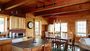 A wooden cabin interior with a kitchen, dining area, and a cozy living space.