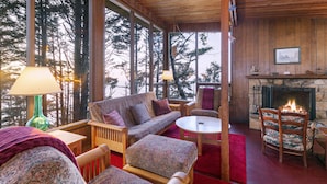 A cozy room with a large window, a fireplace, and a sofa.