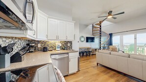 Una cocina moderna con armarios blancos, lavavajillas y un comedor con vistas.