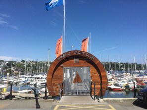 The entrance to Kinsale Yacht Club with a wooden archway, a metal gate, and flags.