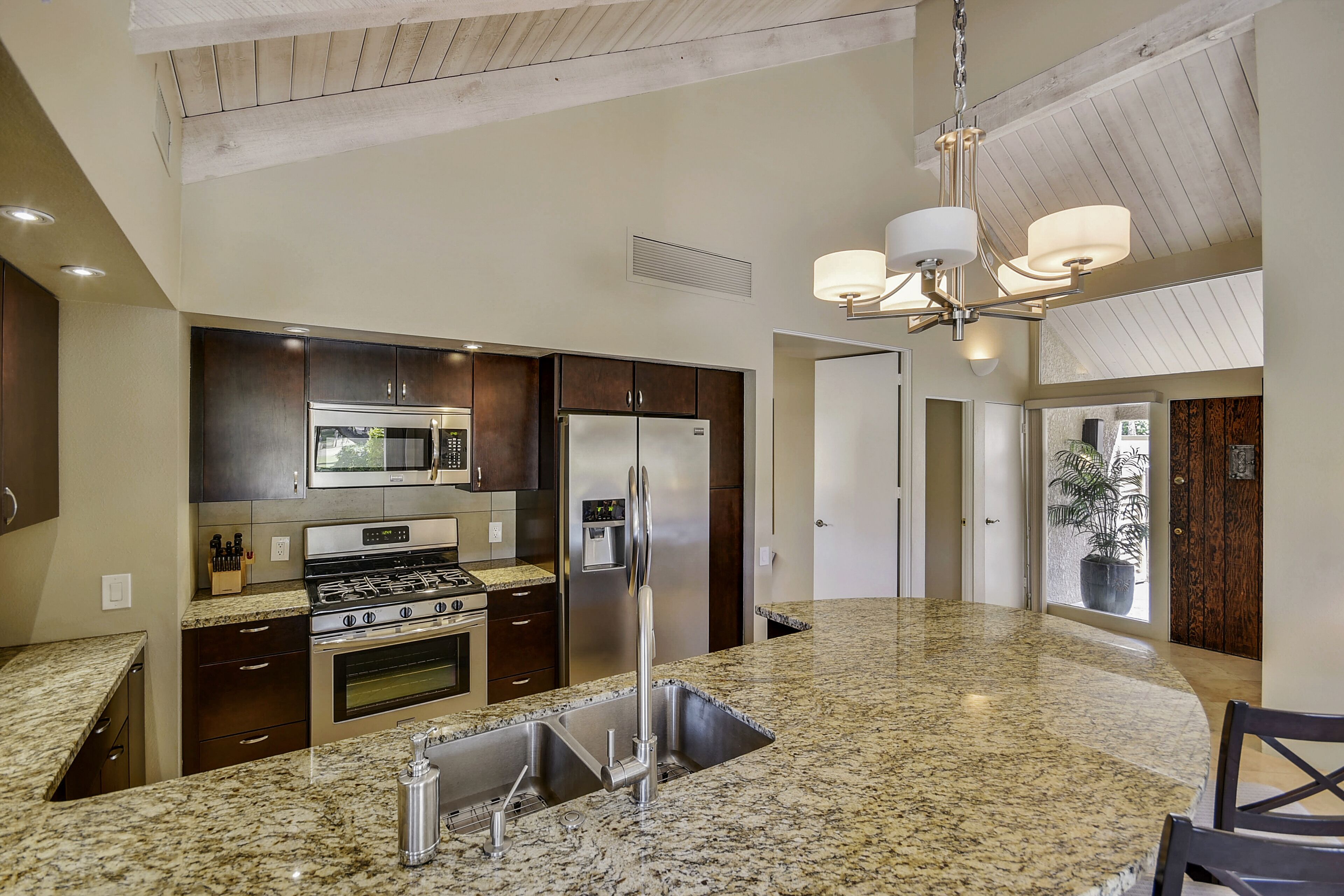 A modern kitchen with granite countertops, stainless steel appliances, and a central island.