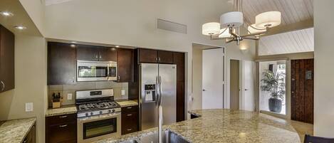 A modern kitchen with granite countertops, stainless steel appliances, and a central island.