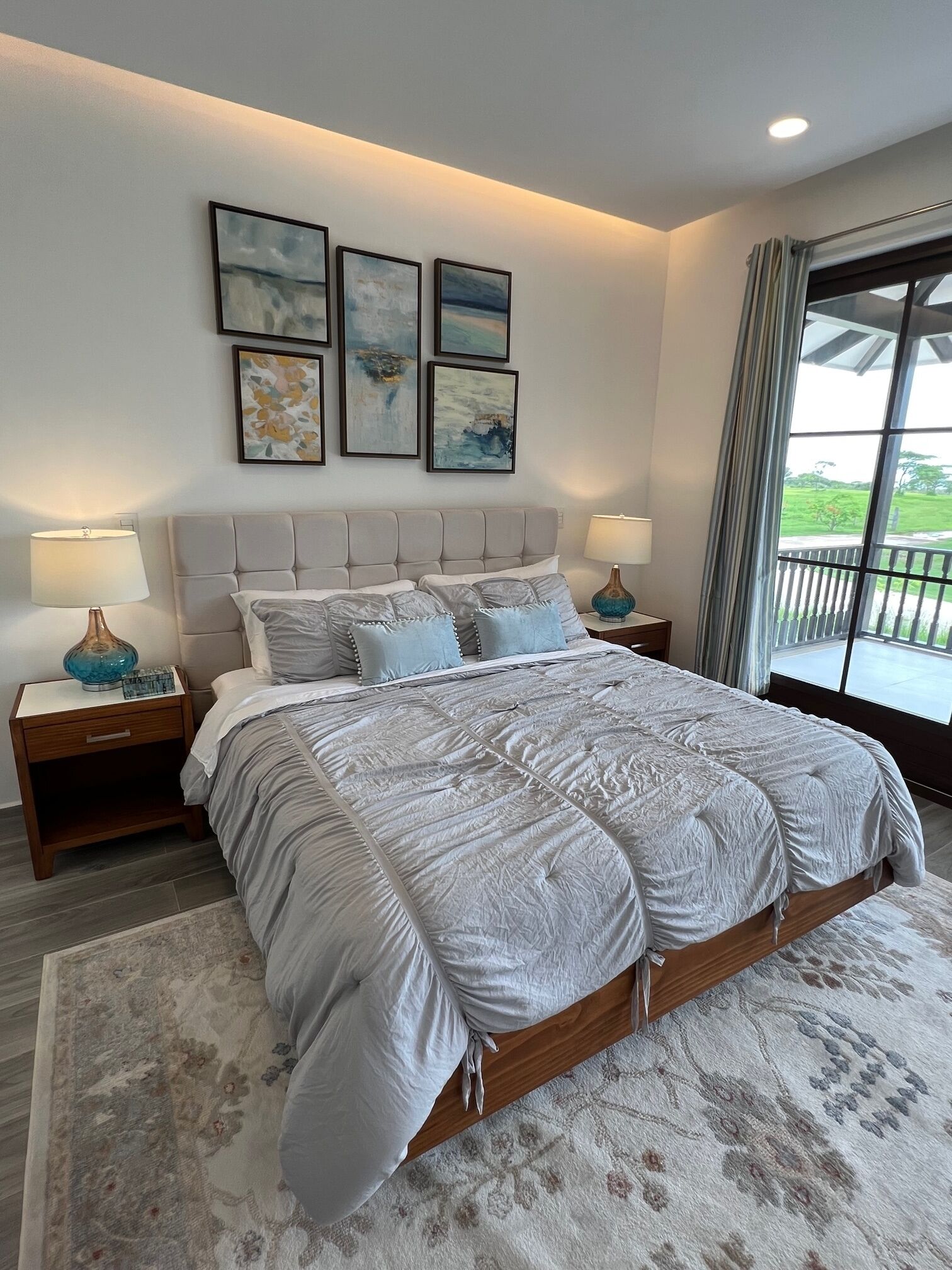 Een slaapkamer met een groot bed, twee nachtkastjes en een raam met uitzicht op groen.