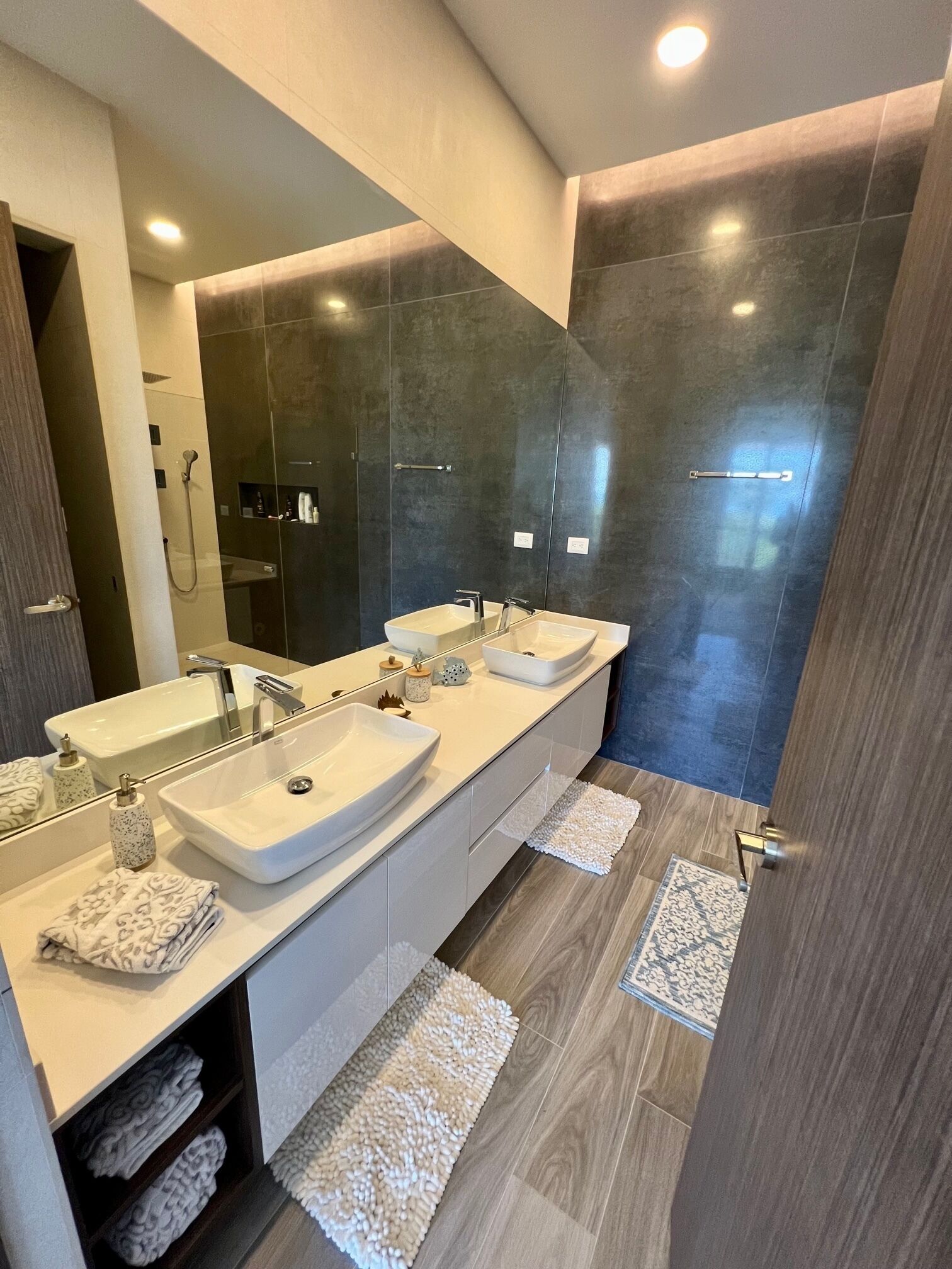 Une salle de bain moderne avec deux lavabos, un grand miroir et un espace douche.