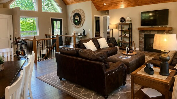 A spacious living area with a high ceiling, a fireplace, a television, and a dining area with a staircase. - 15% Fall Special! Lake Luxury: 6BR/6BA w/ Private Dock| Quiet Cove| (LaFollette)