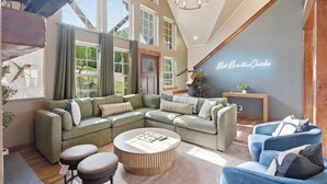 A spacious living room with a sectional sofa, a round coffee table, and a blue armchair. - Lakeview Retreat with Pool, Pickleball Court, Boat Slip, Game Room and Hot Tub (Branson)