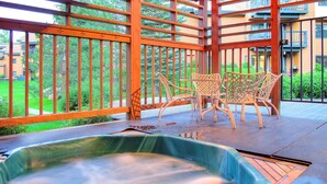 Puurakenteinen pergola, jonka yhteydessä on poreallas. Sen ympärillä on rottinkituoleja, ja sieltä on näkymä asuinalueelle.