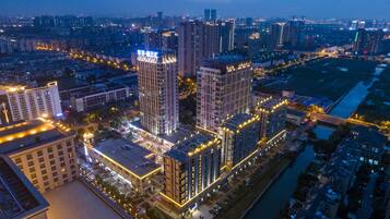 Ett högt byggnadskomplex med flera våningar, omgivet av andra byggnader och en flod.