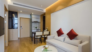 A modern living room with a sofa, ottoman, and dining area. - Pushi Serviced Apartment (Suzhou)