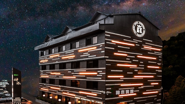 Un hôtel moderne offrant une vue imprenable sur le ciel étoilé, avec un éclairage horizontal mettant en valeur l’architecture et un logo bien visible.