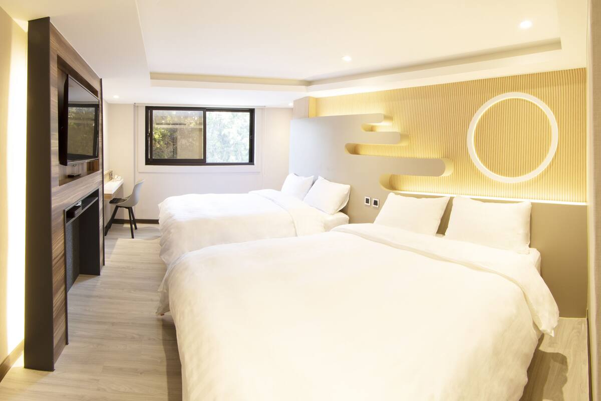 Une chambre d’hôtel moderne équipée de deux lits, d’un bureau et d’une télévision.