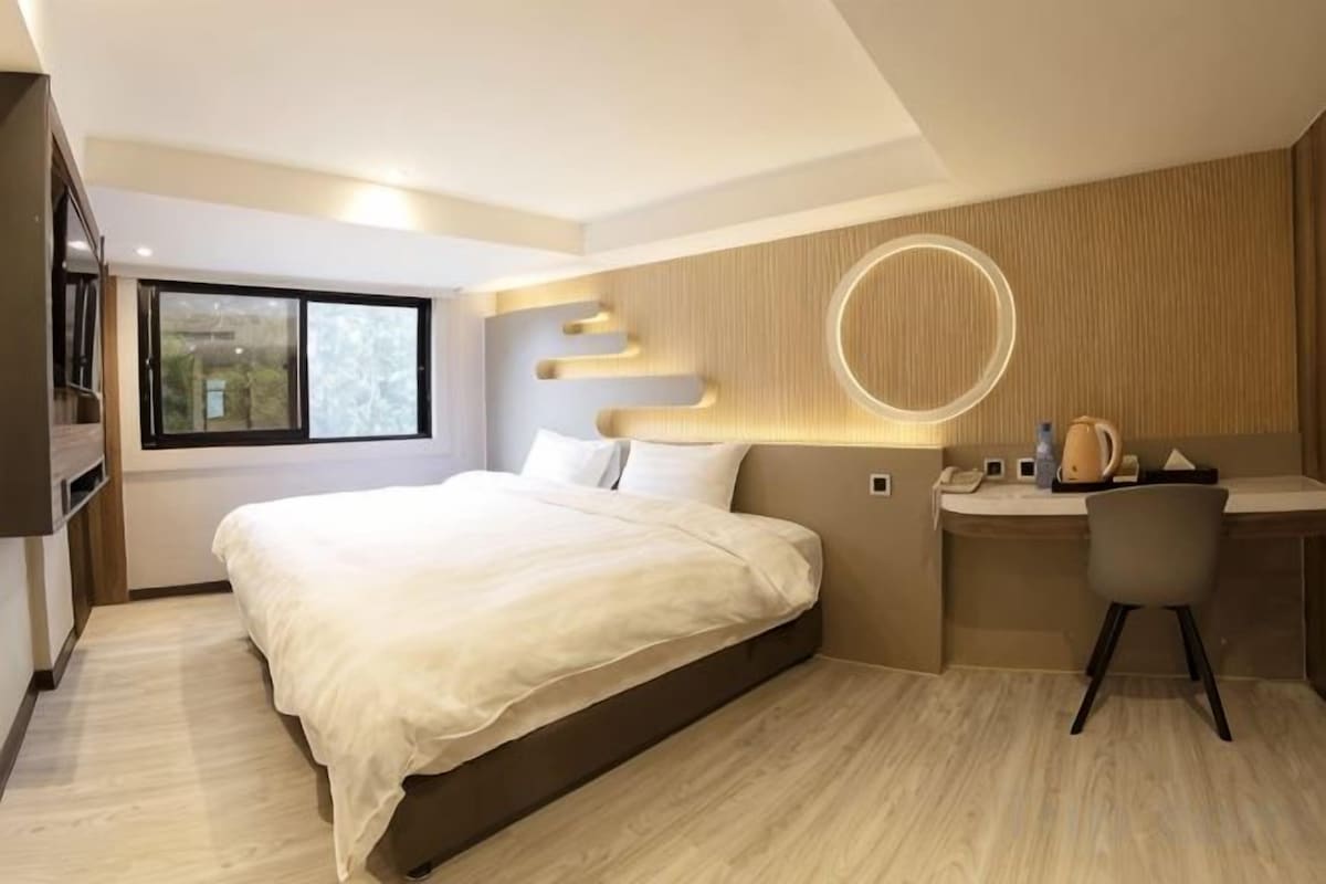 A modern bedroom with a large bed, a desk, and a chair.