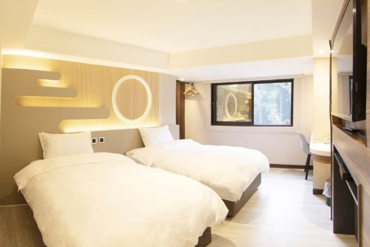 Une chambre d’hôtel avec deux lits, une télévision et une grande fenêtre.