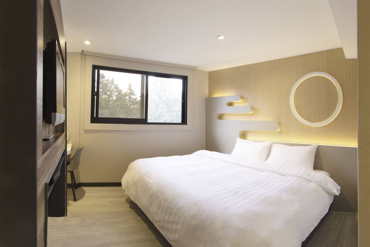 Une chambre moderne avec un grand lit, un bureau et une fenêtre.