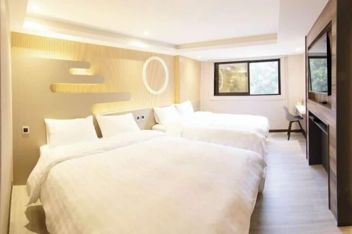Ett hotellrum med två sängar, en TV, ett skrivbord och ett fönster.