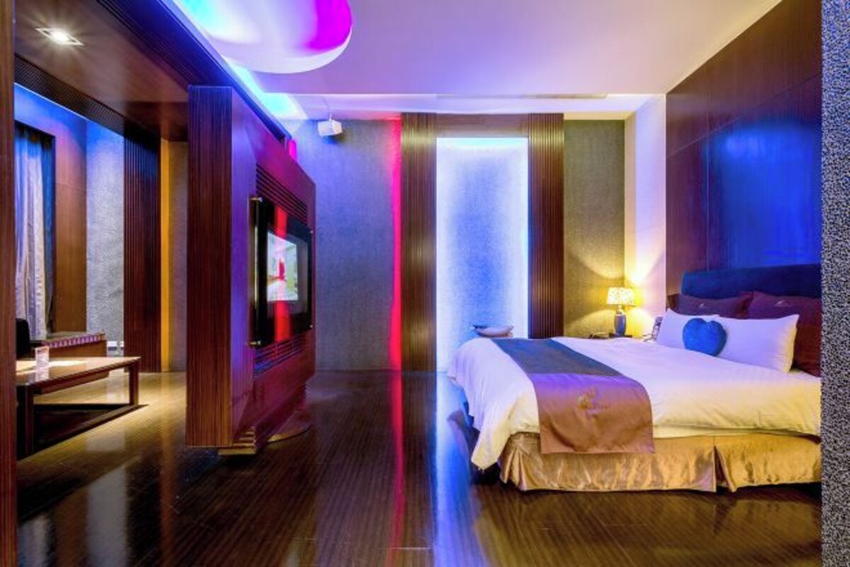 A modern hotel room with a large bed, a TV, and a desk.
