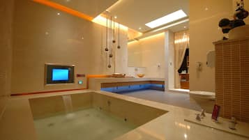 A modern bathroom with a large bathtub, a digital control panel, and a sink area.