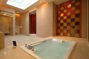 Une salle de bain moderne avec une grande baignoire, une douche en verre et un sol carrelé.