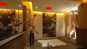 Ein modernes Badezimmer mit einem großen Spiegel, einer Badewanne und dekorativen Blumen.