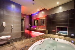 Une salle de bain moderne avec une grande baignoire, des toilettes et un meuble-lavabo avec un miroir.