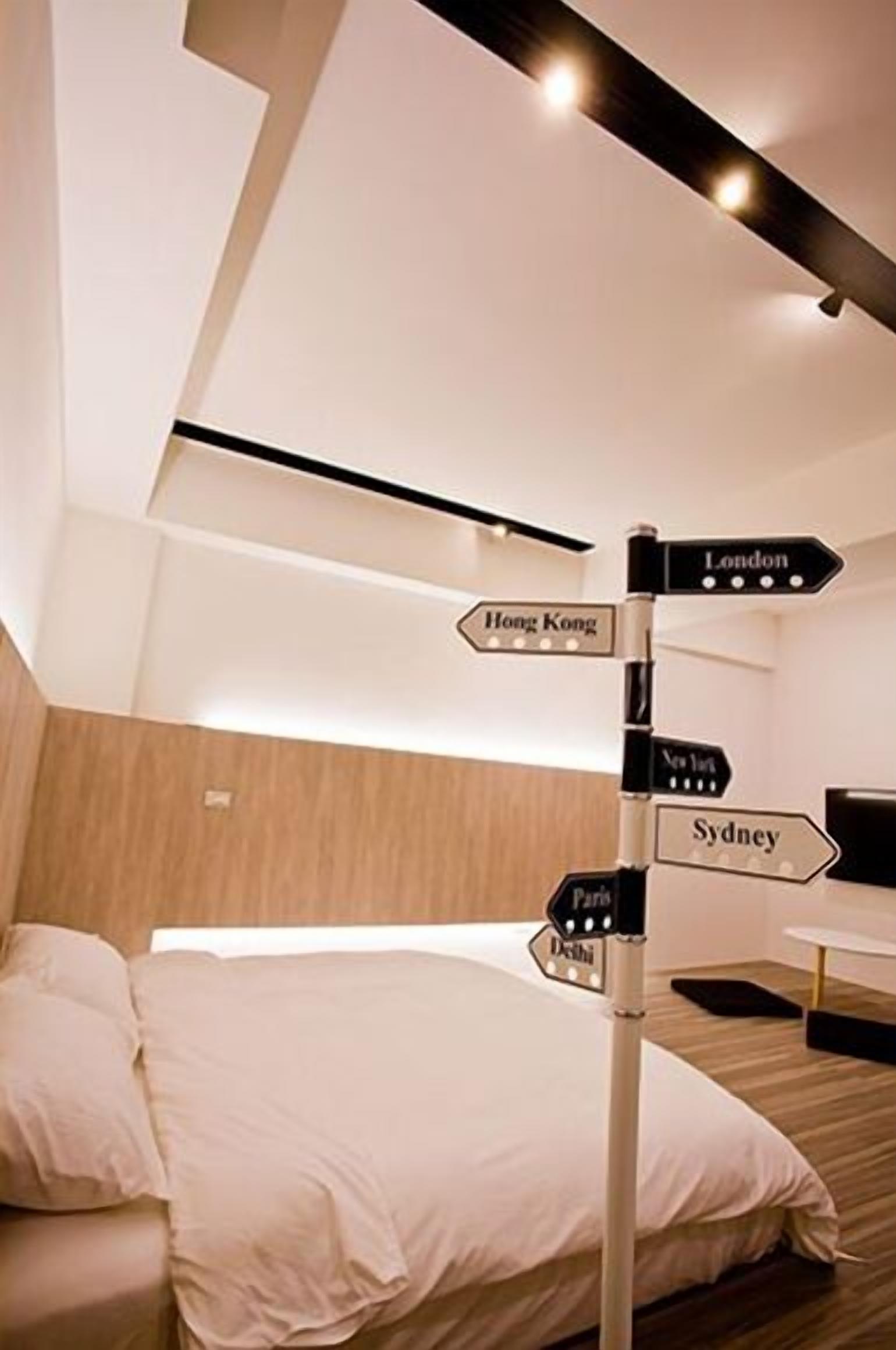 A modern hotel room with a bed, a directional signpost, and a wooden headboard.
