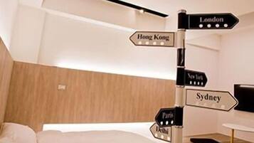 A modern hotel room with a bed, a directional signpost, and a wooden headboard.