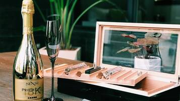 A bottle of Sensi Prosecco, a wine glass, and a wooden box with a corkscrew and other items on a wooden table.
