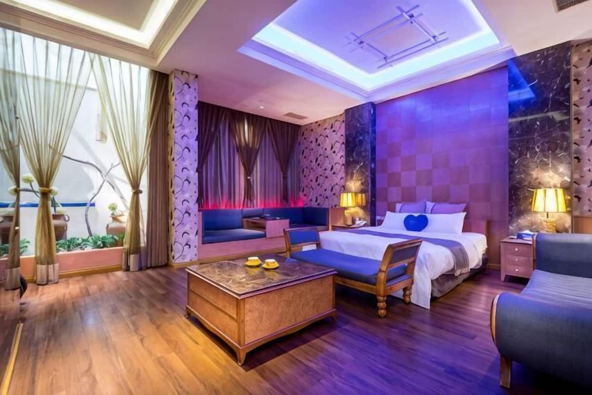 A hotel room with a bed, sofa, coffee table, and a skylight.