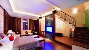 A modern hotel room with a bed, seating area, and a staircase. - Blue Coast Spa Motel (Keelung)